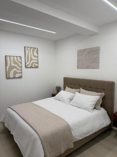 a bedroom with a white bed with three pictures on the wall at XIII Tempio in Cisterna di Latina