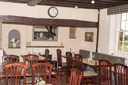 スワドリンコートにあるザ ブルズ ヘッドのテーブルと椅子、壁掛け時計のあるレストラン