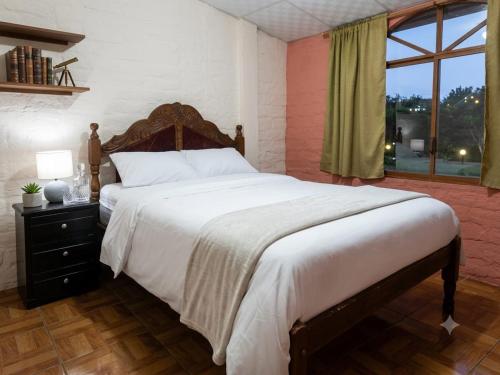 a bedroom with a large bed and a window at Casa Refugio del Amanecer en Baños de Agua Santa in Lligua