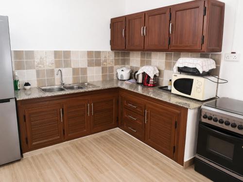 a kitchen with wooden cabinets and a sink and a microwave at Villa Saint Malo in Pereybere