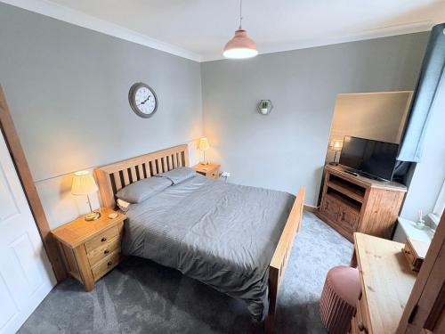 a bedroom with a bed and a clock on the wall at The Oaks Cottage in Penrith