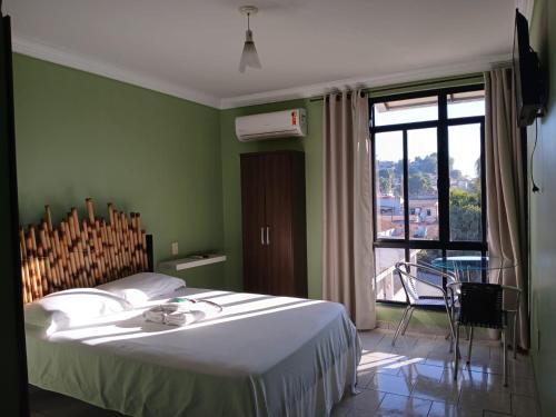 a bedroom with a bed and a large window at Paradise Hostel e Suítes in Itatiaia