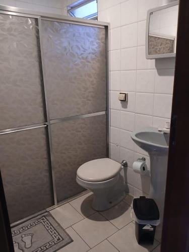 a bathroom with a shower with a toilet and a sink at Paradise Hostel e Suítes in Itatiaia