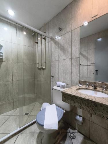 a bathroom with a toilet and a sink and a shower at Stratus Vila Hotel in Volta Redonda