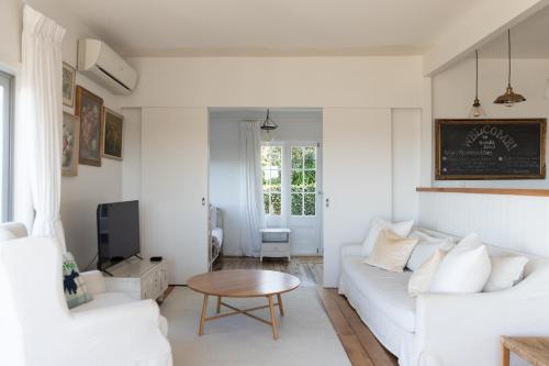 a living room with a white couch and a table at The Vintage Cottage in Oneroa