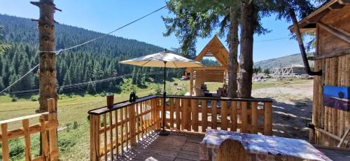 a wooden deck with an umbrella on top of it at Pinetrees Lodge Hostel in Nadgrad