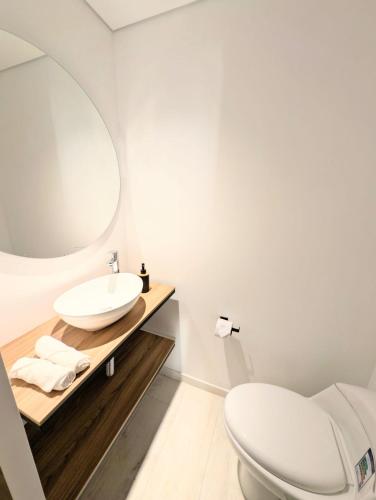 a white bathroom with a sink and a toilet at Iwana stay in Bogotá