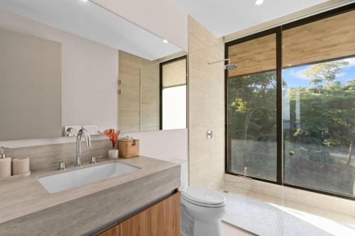 a bathroom with a sink and a toilet and a window at Oceanview Penthouse - Private Pool - Reserva Conchal in Playa Conchal