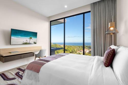 a bedroom with a bed and a desk with a large window at Oceanview Penthouse - Private Pool - Reserva Conchal in Playa Conchal
