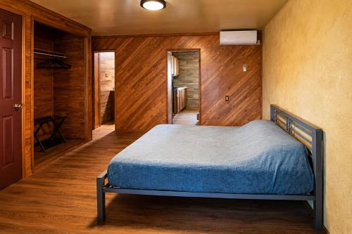 a bedroom with a bed in a room with wooden walls at The Mint Motel in Arlington
