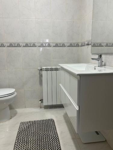 a white bathroom with a sink and a toilet at Casa do Evaristo in Nabais