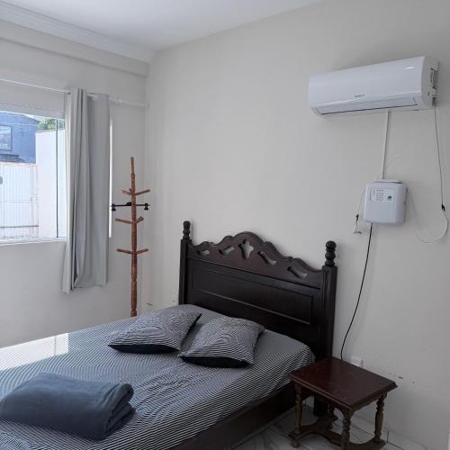 a bedroom with a bed and a lamp and a window at Casa de 2 QUARTOS COM PISCINA in Balneário Camboriú