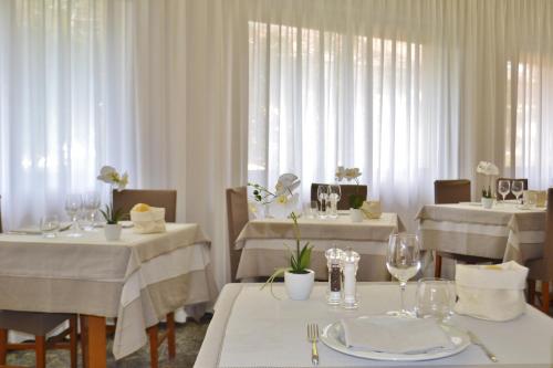 a dining room with white tables and white curtains at Gold Hotel in Bordighera