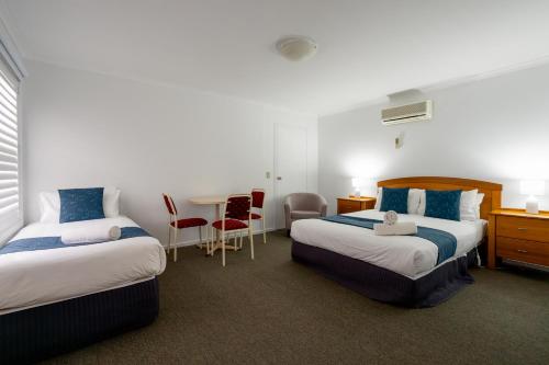 a hotel room with two beds and a table at Waves on Banyan formerly Comfort Inn International in Warrnambool