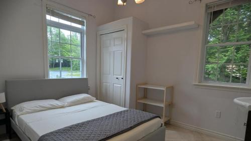 a bedroom with a bed and a sink and two windows at Happy Moose Guest Suite in Porters Lake
