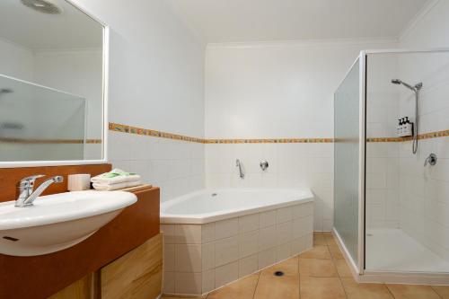 a bathroom with a tub and a sink and a shower at Waves on Banyan formerly Comfort Inn International in Warrnambool