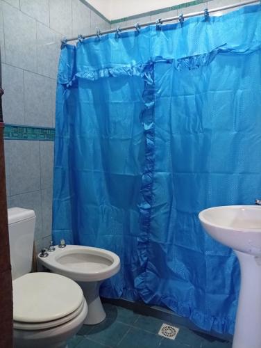 a bathroom with a toilet and a blue shower curtain at Maimara Hospedaje Sumalawa in Maimará