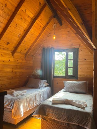 a bedroom with two beds in a wooden cabin at Cabanas em Canela - Leão da Tribo de Judá- Refúgio com Piscina in Canela