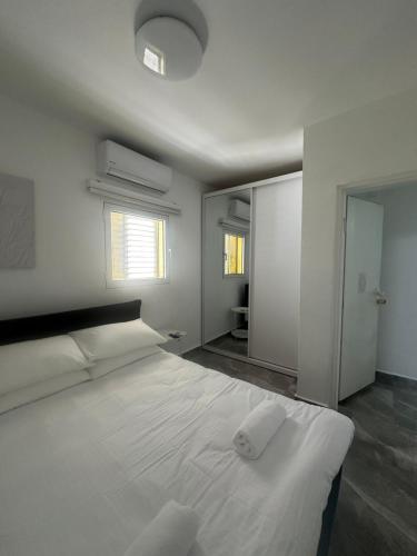 a bedroom with a large white bed and a mirror at Beachfront Haven - Perfect for Groups in Ashdod