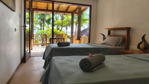 a bedroom with two beds and a door to a porch at Castaway Surf Retreat in Sekongkang