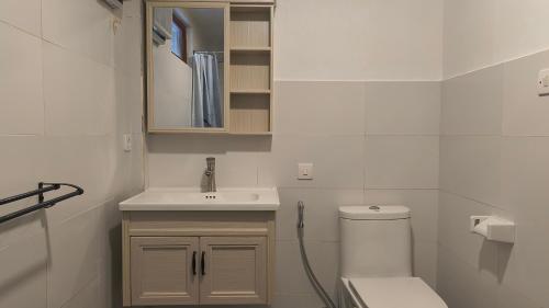 a white bathroom with a toilet and a sink at Castaway Surf Retreat in Sekongkang