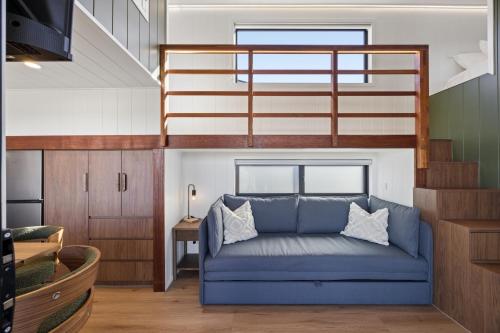 a living room with a blue couch and a staircase at Ginger GOAT - Luxury New Tiny Home in Jindabyne