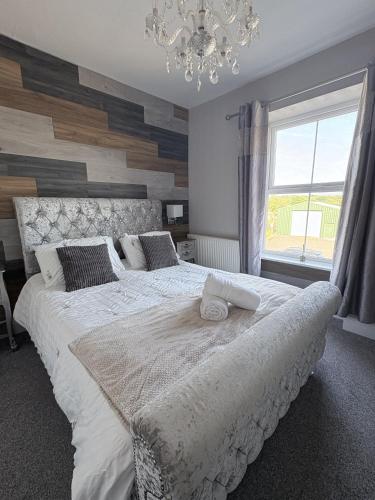 a bedroom with a large white bed with a chandelier at Taldrwst At Dwyran in Dwyran
