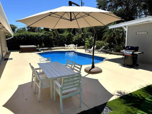 a table and chairs with an umbrella next to a pool at Jupiter Heated Pool/Spa Luxury 3Bed Home in Jupiter