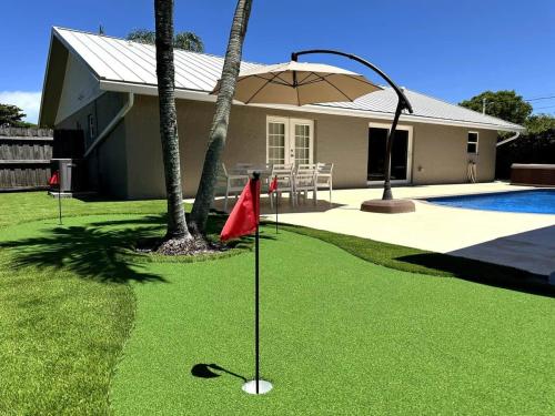 a putting green with a red flag in front of a house at Jupiter Heated Pool/Spa Luxury 3Bed Home in Jupiter