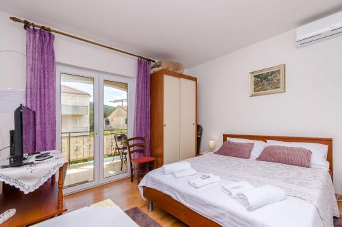 a bedroom with a bed and a desk and a window at Apartments Emmas studio in Stari Grad