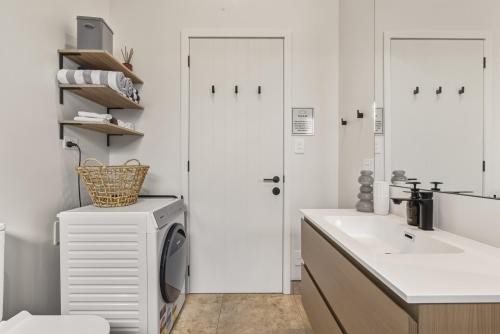 a bathroom with a sink and a washing machine at Roam Taupo Upper Terrace Unit 3 - Spa Pool in Taupo