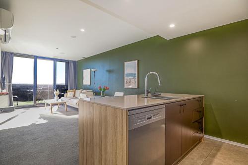 a kitchen with a sink and a living room at Lakeview on Grazier in Belconnen