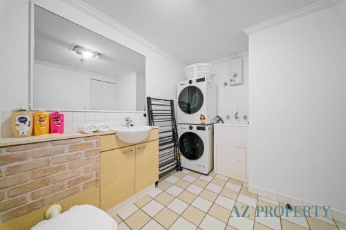 a kitchen with a sink and a washing machine at Perth CBD Hideaway Walk to Everything in Perth