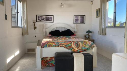 a white bedroom with a bed with a colorful blanket at Casa para 6 personas con vista al mar Cumbre del Diablo 3 in Punta Del Diablo
