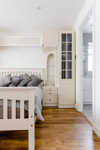 a white bedroom with a white bed and wooden floors at Single Room with shared bathroom in Cheshunt