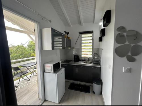 a small kitchen with a sink and a microwave at Bungalow Kaz à Céli in Deshaies