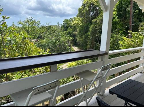 a porch with a table and a chair and trees at Bungalow Kaz à Céli in Deshaies