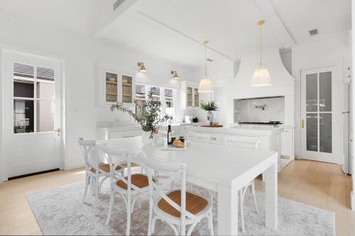 a white kitchen with a white table and chairs at Farmhouse Hunter Valley in Pokolbin