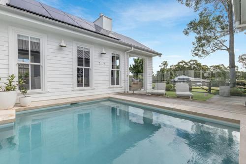 a swimming pool in front of a house at Farmhouse Hunter Valley in Pokolbin