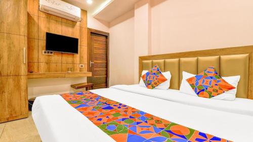 a hotel room with two beds and a tv at Ganges Pride Hotel in Haridwār