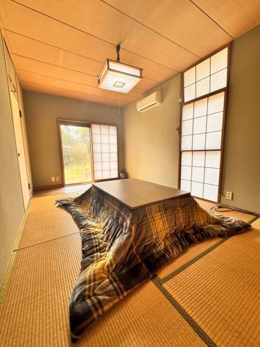 a large bed in the middle of a room with windows at トラストメゾン荻 in Ito