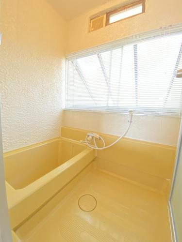 a bathroom with a bath tub and a window at トラストメゾン荻 in Ito