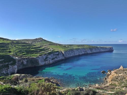 a cave in the ocean next to a cliff at North Side Apartment 1 in Mġarr