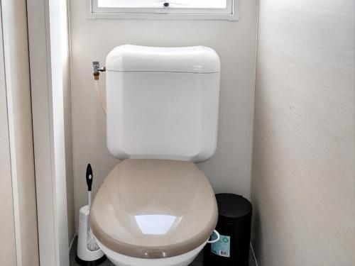 a small bathroom with a white toilet with a window at Breebos Chalet near Antwerp Camp in Rijkevorsel