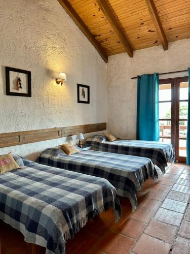 three beds in a room with blue curtains at Brisas del Diablo 1 in Punta Del Diablo