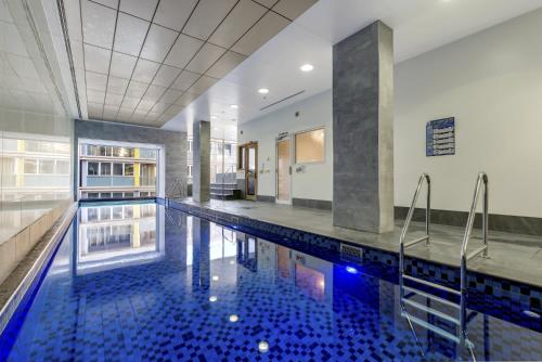 a swimming pool in a building with a blue tile floor at 2BR CBD Apt Swimming Pool Sauna SPA CBD in Adelaide