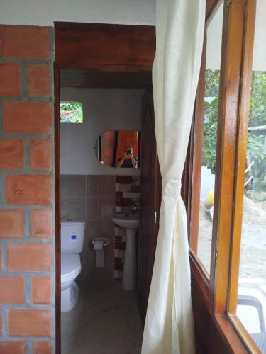 a person taking a picture of a bathroom with a mirror at Cabañas orquídea in Norcasia