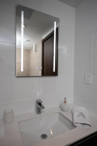 a white bathroom with a tub and a mirror at Ceiling INARA 1503 B in Guatemala