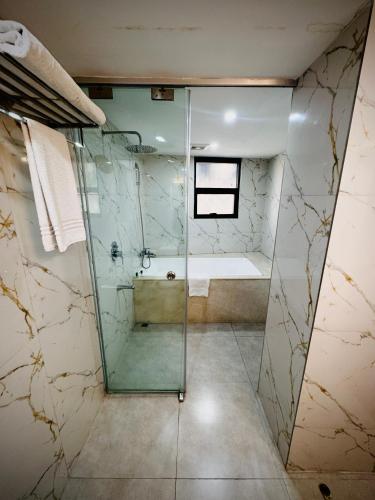 a bathroom with a glass shower with a tub at Dhaka Unique Regency in Dhaka