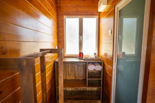 a small bathroom with a window and wooden walls at Leopard Inn Arugam Bay in Arugam Bay